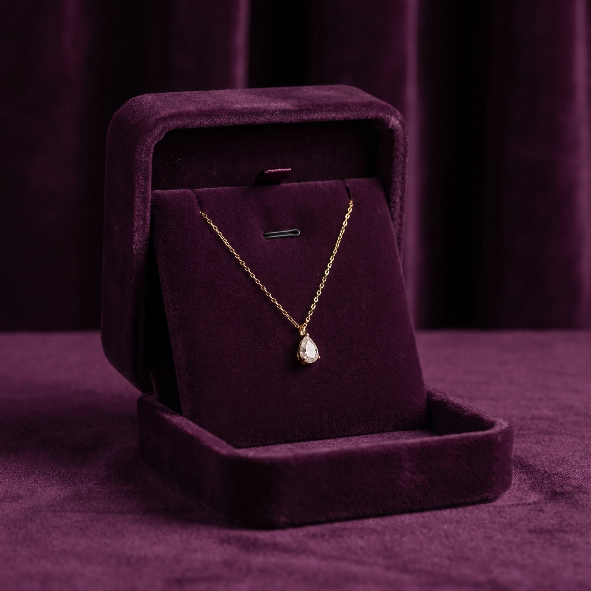 Gold necklace with a pendant in a purple jewelry box on a matching purple background