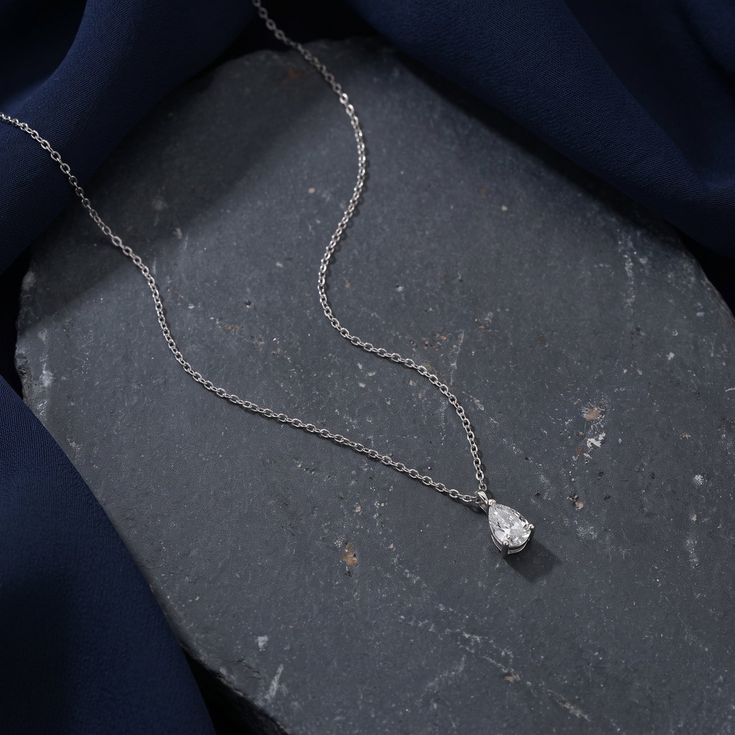 Silver necklace with a pendant on a dark stone surface