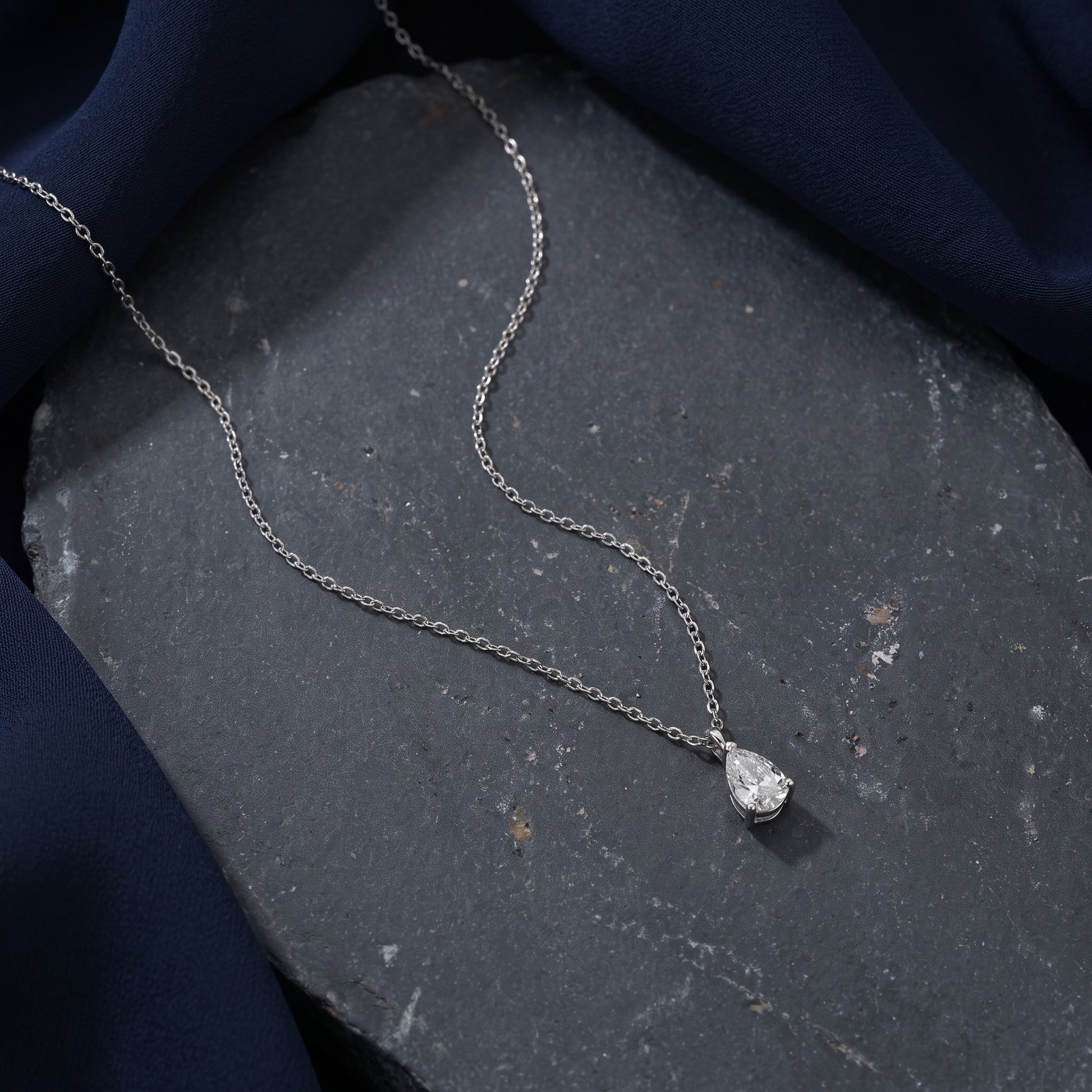 Silver necklace with a pendant on a dark stone surface