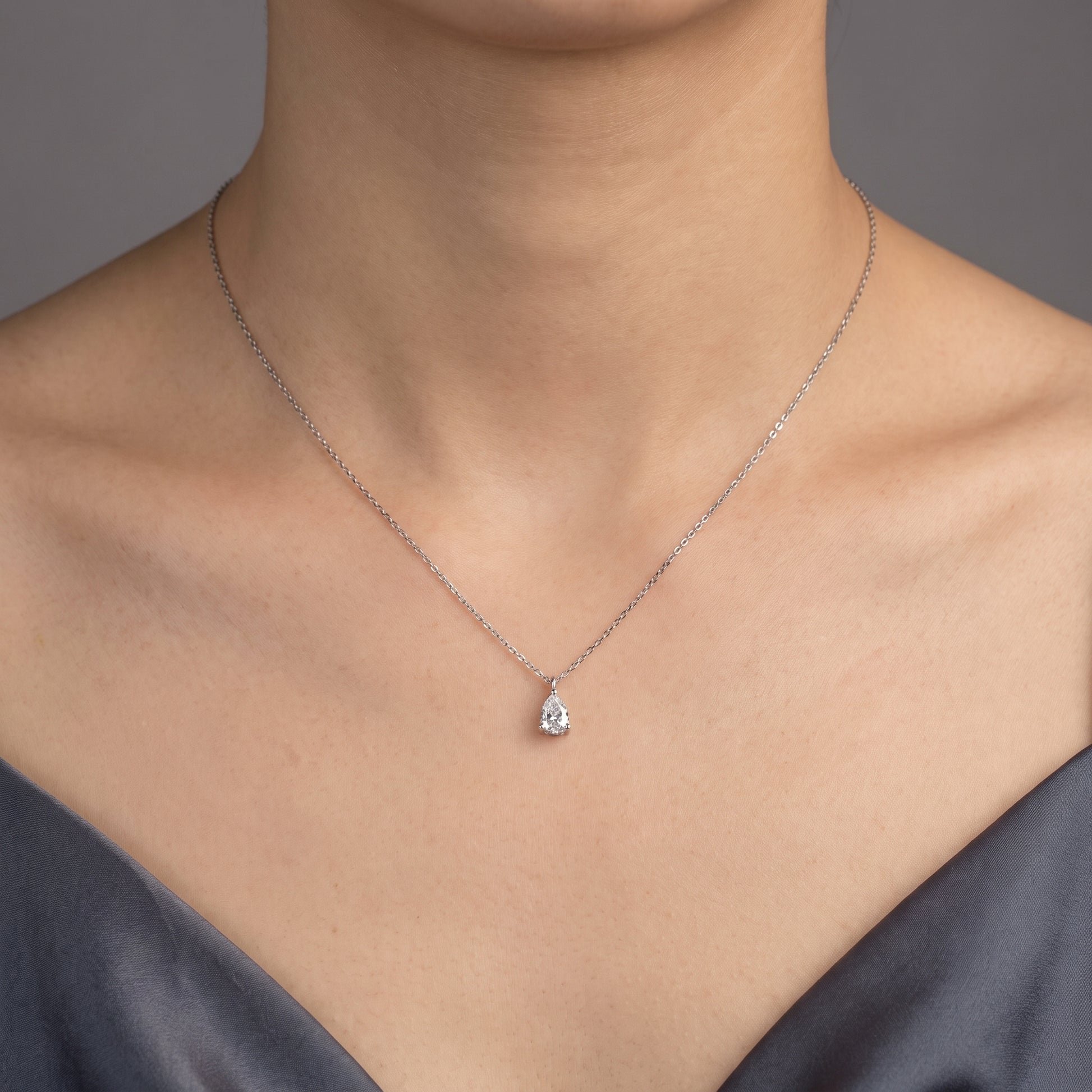 Necklace with a pendant on a person wearing a black top against a gray background